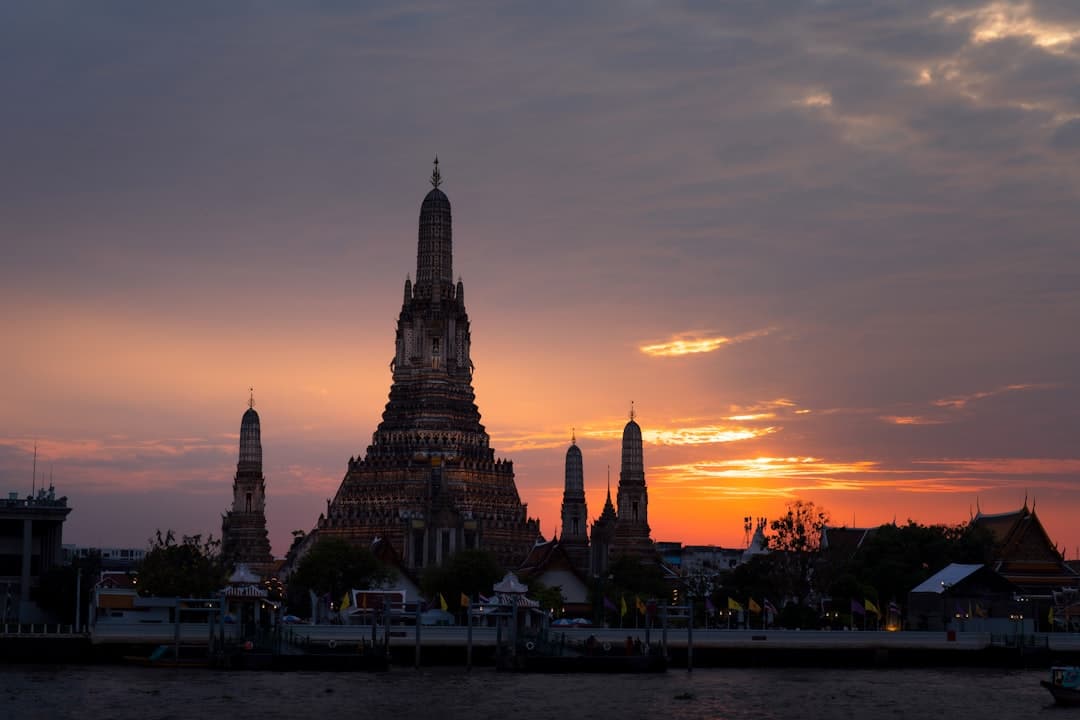 Wat arun temple silhouetted against a vibrant sunset sky
