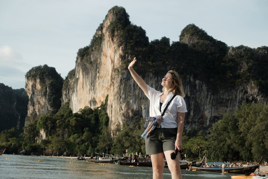 Woman raises hand against dramatic cliffs by the sea